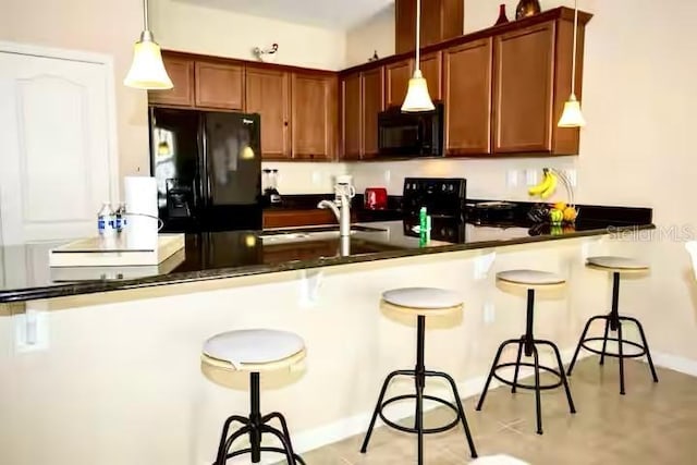 kitchen with dark countertops, hanging light fixtures, a peninsula, and black appliances