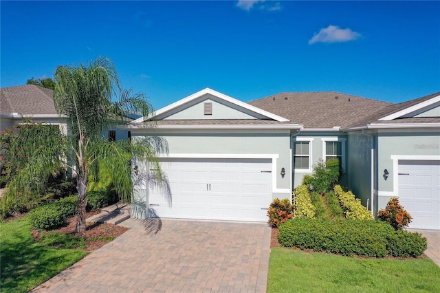 ranch-style house with stucco siding, decorative driveway, and a garage