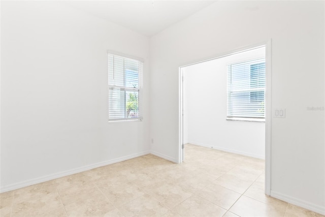 spare room featuring baseboards and light tile patterned flooring