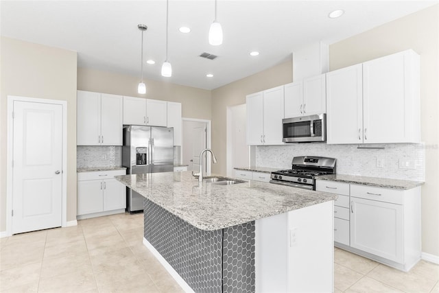 kitchen featuring light stone countertops, a center island with sink, stainless steel appliances, white cabinetry, and a sink