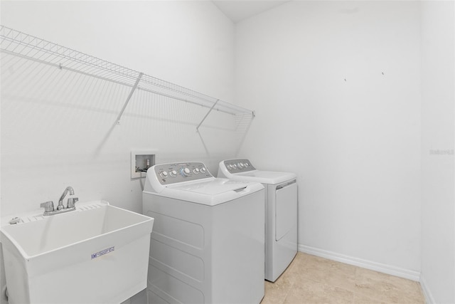 laundry room with laundry area, washing machine and dryer, baseboards, and a sink