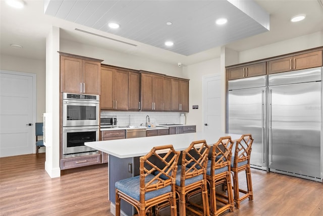 kitchen with light countertops, backsplash, wood finished floors, and appliances with stainless steel finishes