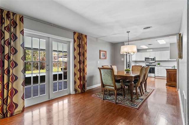 dining space with visible vents, french doors, baseboards, and wood finished floors