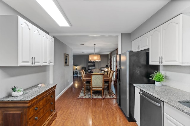 kitchen with dishwasher, light stone counters, light wood-style flooring, hanging light fixtures, and white cabinetry