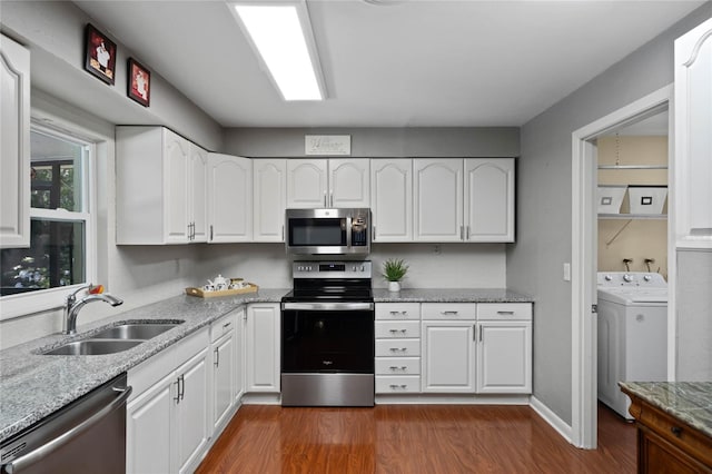 kitchen featuring a sink, washer / clothes dryer, dark wood finished floors, stainless steel appliances, and white cabinets