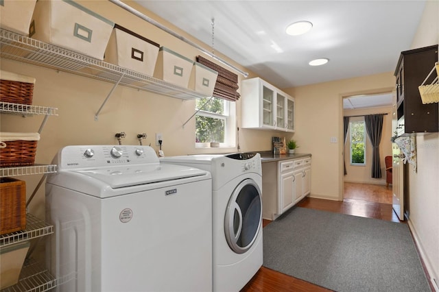 clothes washing area featuring cabinet space, separate washer and dryer, a healthy amount of sunlight, and dark wood-type flooring