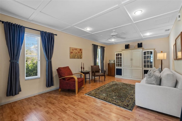 living area featuring light wood finished floors, coffered ceiling, baseboards, and a ceiling fan