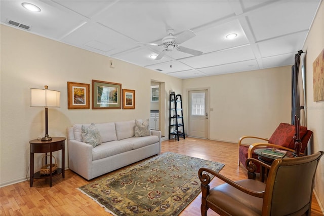 living room with light wood finished floors, visible vents, baseboards, coffered ceiling, and a ceiling fan