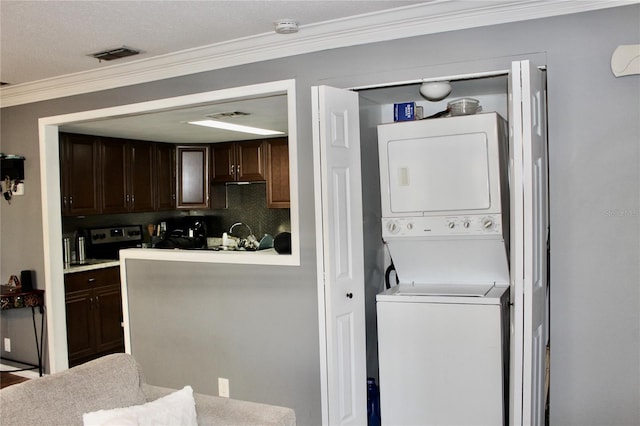 washroom featuring laundry area, crown molding, visible vents, and stacked washing maching and dryer