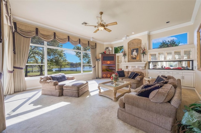 carpeted living area with visible vents, a water view, a ceiling fan, crown molding, and a tile fireplace