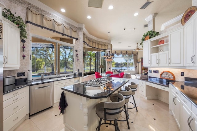 kitchen with visible vents, a kitchen island, crown molding, appliances with stainless steel finishes, and white cabinetry