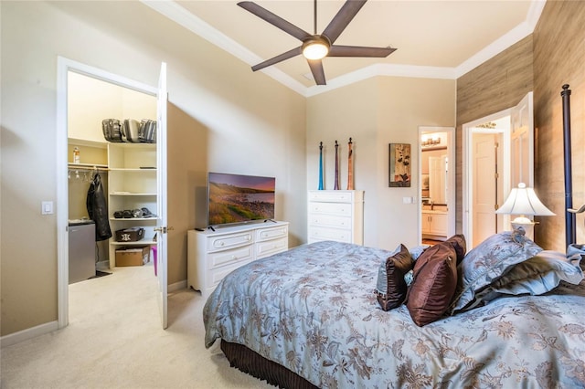 bedroom with baseboards, a closet, a walk in closet, crown molding, and light colored carpet