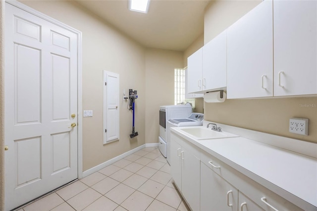 clothes washing area with washer and clothes dryer, a sink, cabinet space, light tile patterned floors, and baseboards