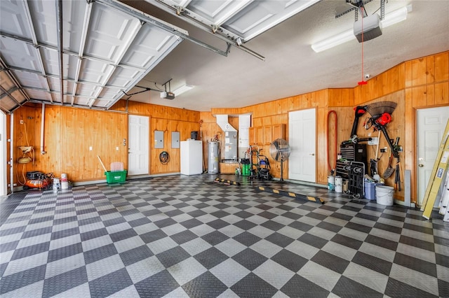 garage with electric panel, wooden walls, a garage door opener, and electric water heater