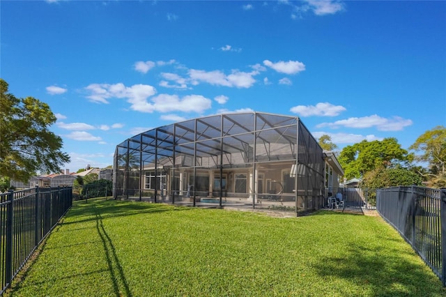 rear view of property with glass enclosure, a lawn, a fenced backyard, and a fenced in pool