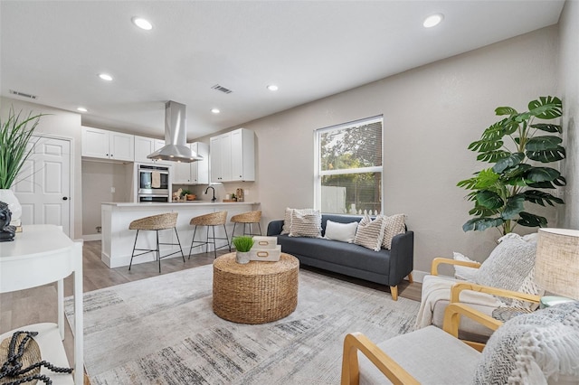 living area with recessed lighting, light wood-style floors, visible vents, and baseboards