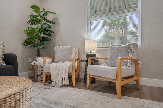 sitting room with baseboards, wood finished floors, and a textured wall