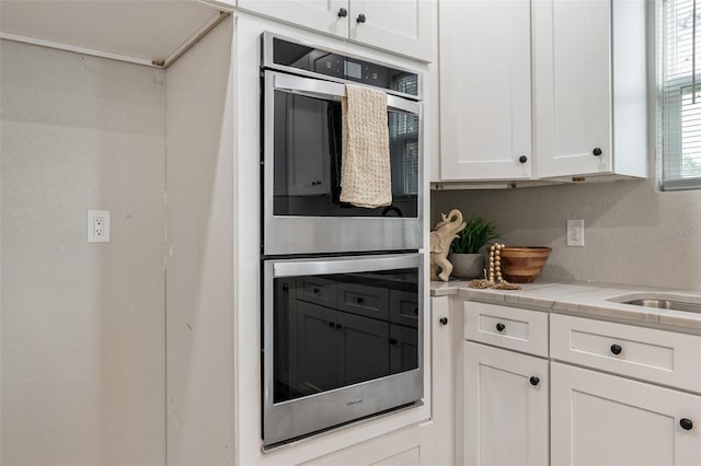 kitchen with double oven, light countertops, and white cabinetry