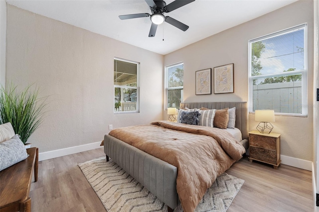 bedroom featuring multiple windows, light wood-style floors, and baseboards