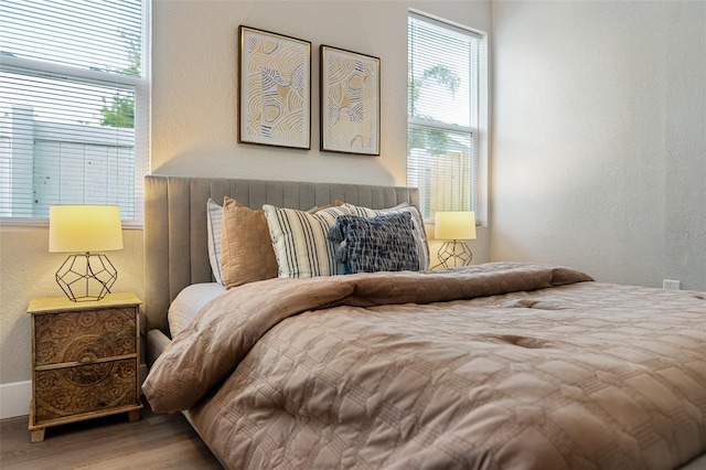 bedroom with a textured wall and wood finished floors