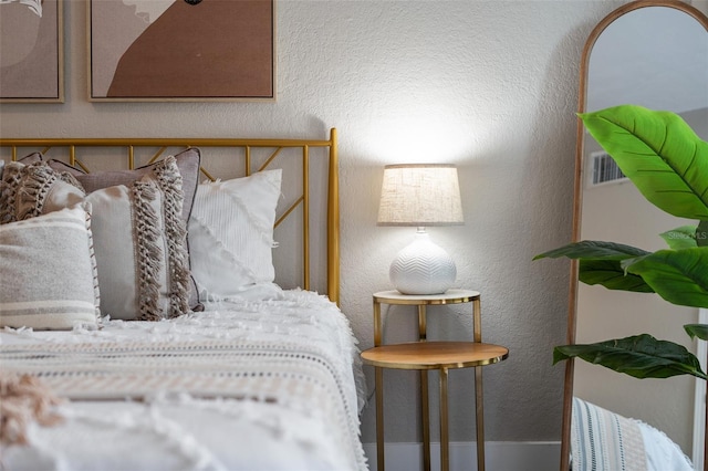 bedroom with visible vents and a textured wall