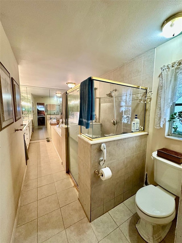 bathroom with tile patterned flooring, a shower stall, toilet, and a textured ceiling