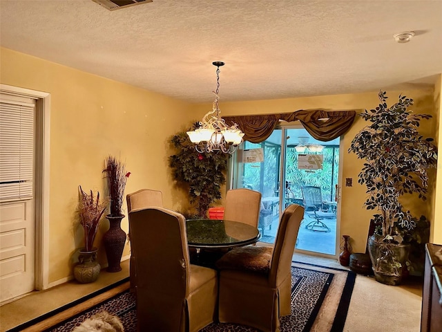 carpeted dining room featuring a textured ceiling and an inviting chandelier