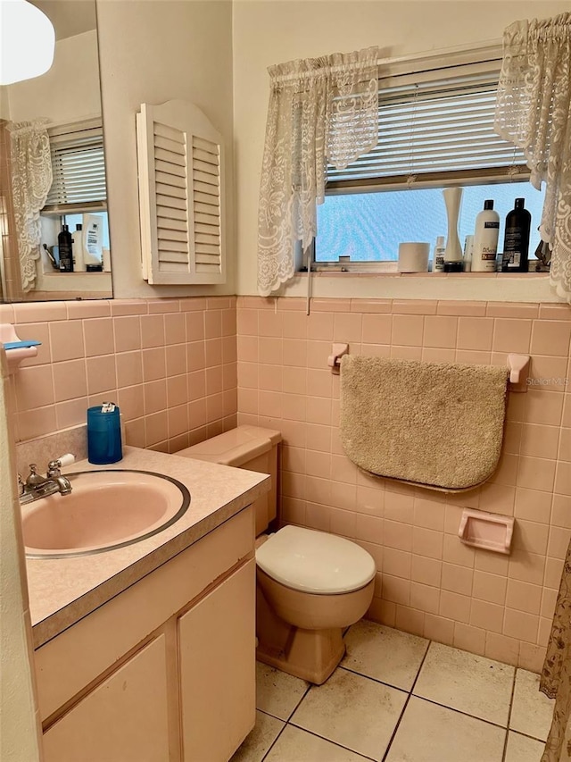 bathroom with tile patterned floors, a wainscoted wall, toilet, tile walls, and vanity