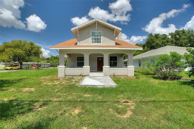 view of front of home with a front yard, covered porch, and stucco siding