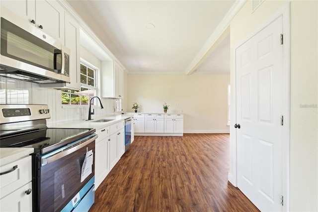 kitchen with dark wood-type flooring, light countertops, ornamental molding, stainless steel appliances, and a sink