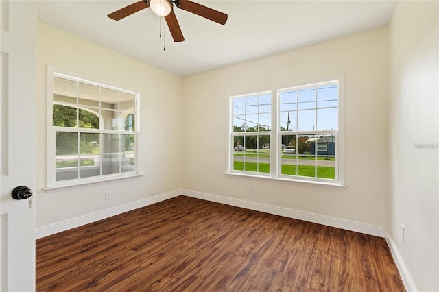 empty room with baseboards, dark wood-type flooring, and ceiling fan