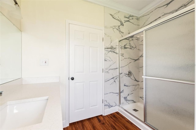 bathroom with a marble finish shower, wood finished floors, crown molding, and a sink