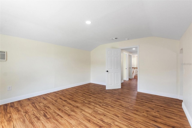 unfurnished room with visible vents, wood finished floors, and vaulted ceiling