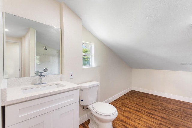 bathroom featuring baseboards, toilet, vaulted ceiling, wood finished floors, and vanity