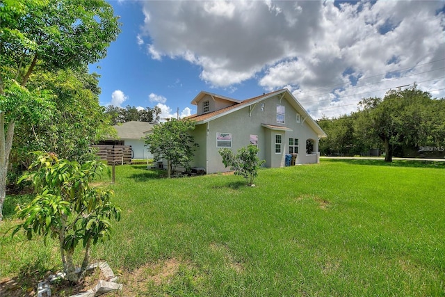 back of house with stucco siding, a lawn, and fence