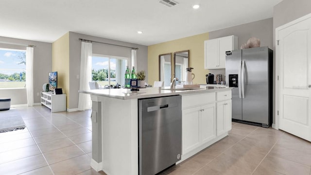 kitchen featuring light tile patterned floors, visible vents, a kitchen island with sink, stainless steel appliances, and light countertops