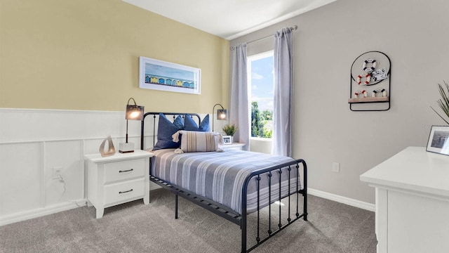 bedroom with a wainscoted wall, carpet flooring, and a decorative wall