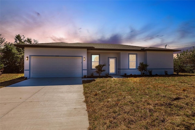 ranch-style home with a garage, concrete driveway, a front yard, and stucco siding