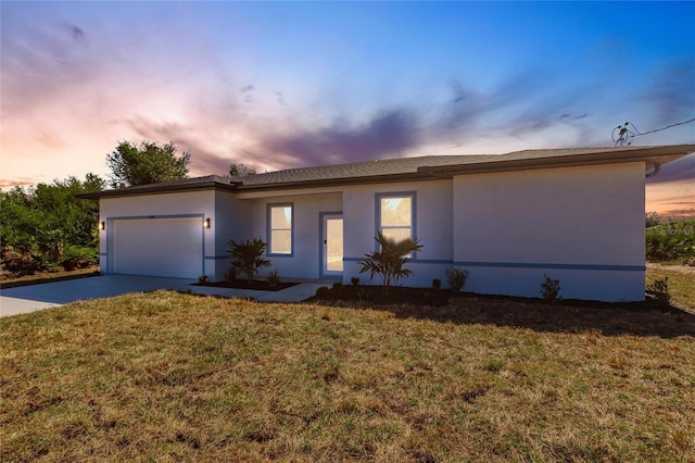 single story home with stucco siding, driveway, a front yard, and a garage