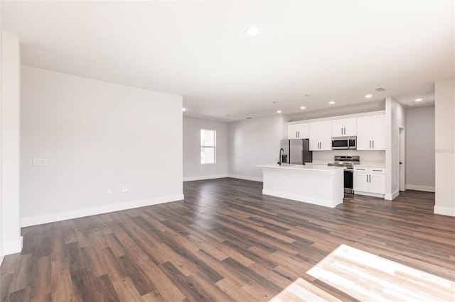 unfurnished living room featuring visible vents, a sink, recessed lighting, baseboards, and dark wood-style flooring