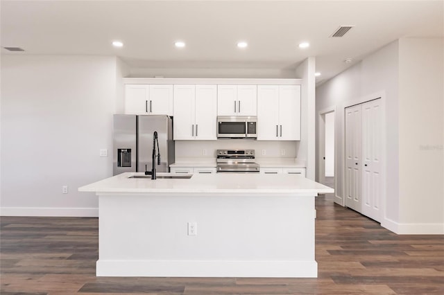 kitchen with visible vents, a kitchen island with sink, a sink, appliances with stainless steel finishes, and white cabinets