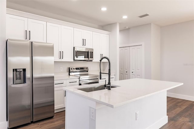 kitchen featuring visible vents, a kitchen island with sink, a sink, stainless steel appliances, and white cabinets