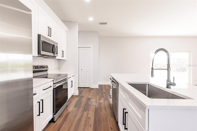 kitchen featuring visible vents, dark wood finished floors, white cabinets, stainless steel appliances, and a sink