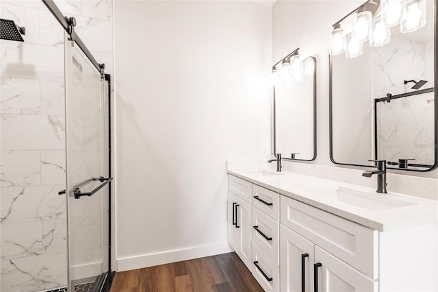 bathroom featuring a stall shower, wood finished floors, baseboards, and a sink