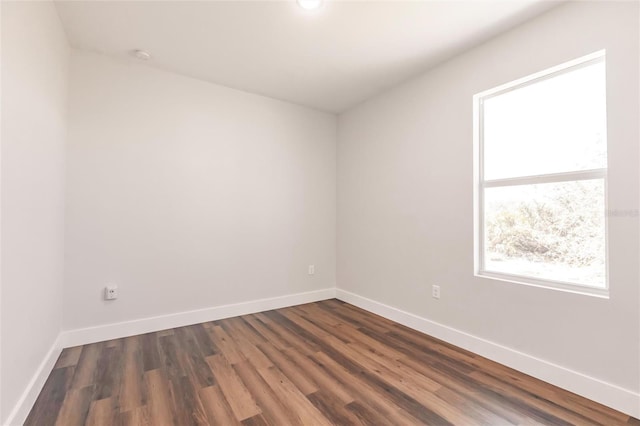 empty room with dark wood finished floors and baseboards