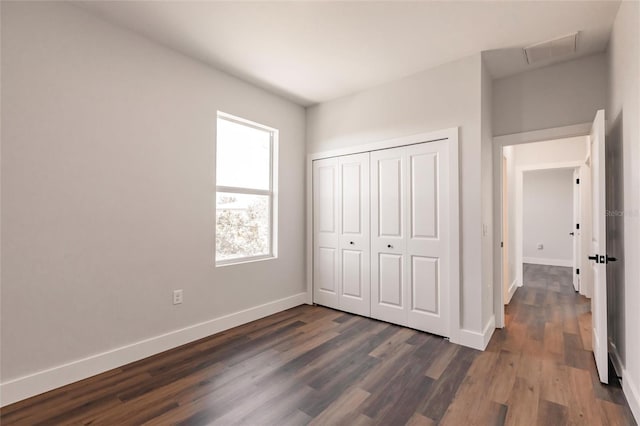 unfurnished bedroom featuring visible vents, baseboards, a closet, and dark wood-style flooring