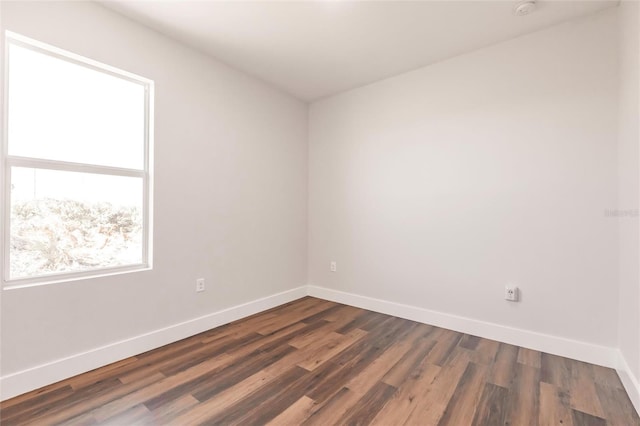 spare room featuring dark wood-type flooring and baseboards