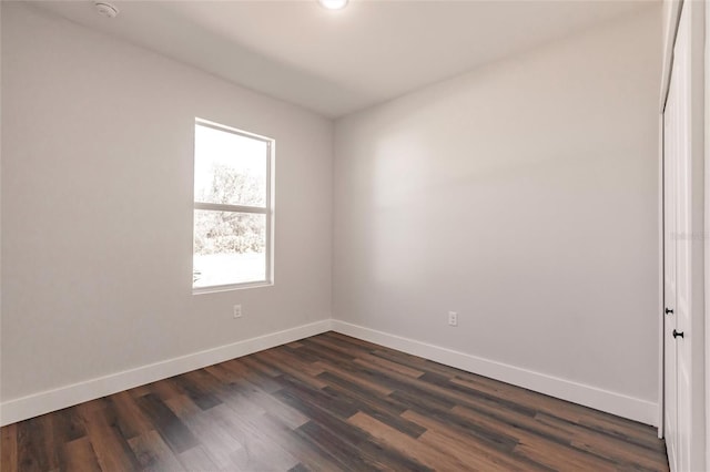 spare room featuring baseboards and dark wood-style flooring