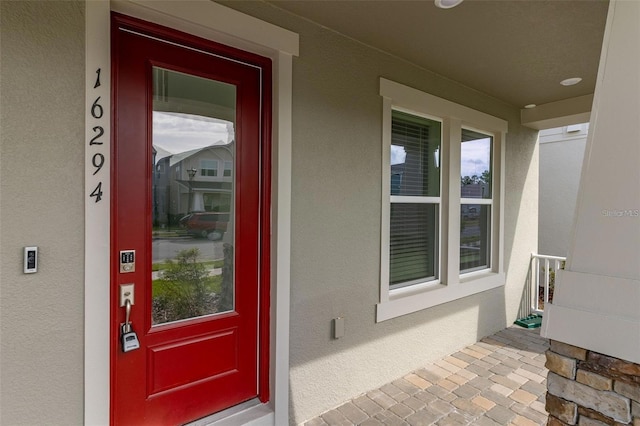 view of exterior entry with stucco siding and a porch