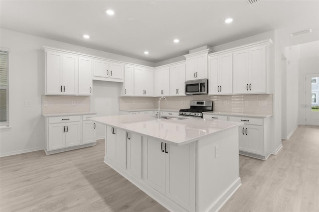 kitchen with a sink, white cabinets, a center island with sink, and stainless steel appliances